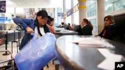 Una mujer carga su equipaje envuelto en el mostrador de boletos antes de su vuelo a Cuba en el Aeropuerto Internacional de Fort Lauderdale (Imagen de Archivo)