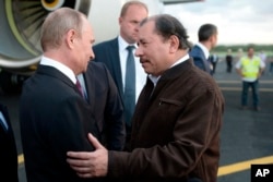 El presidente de Nicaragua, Daniel Ortega, saluda al presidente ruso Vladimir Putin a su llegada al aeropuerto de Managua, Nicaragua, el 11 de julio de 2014. (Foto AP/RIA-Novosti, Alexei Nikolsky, Servicio de Prensa Presidencial)